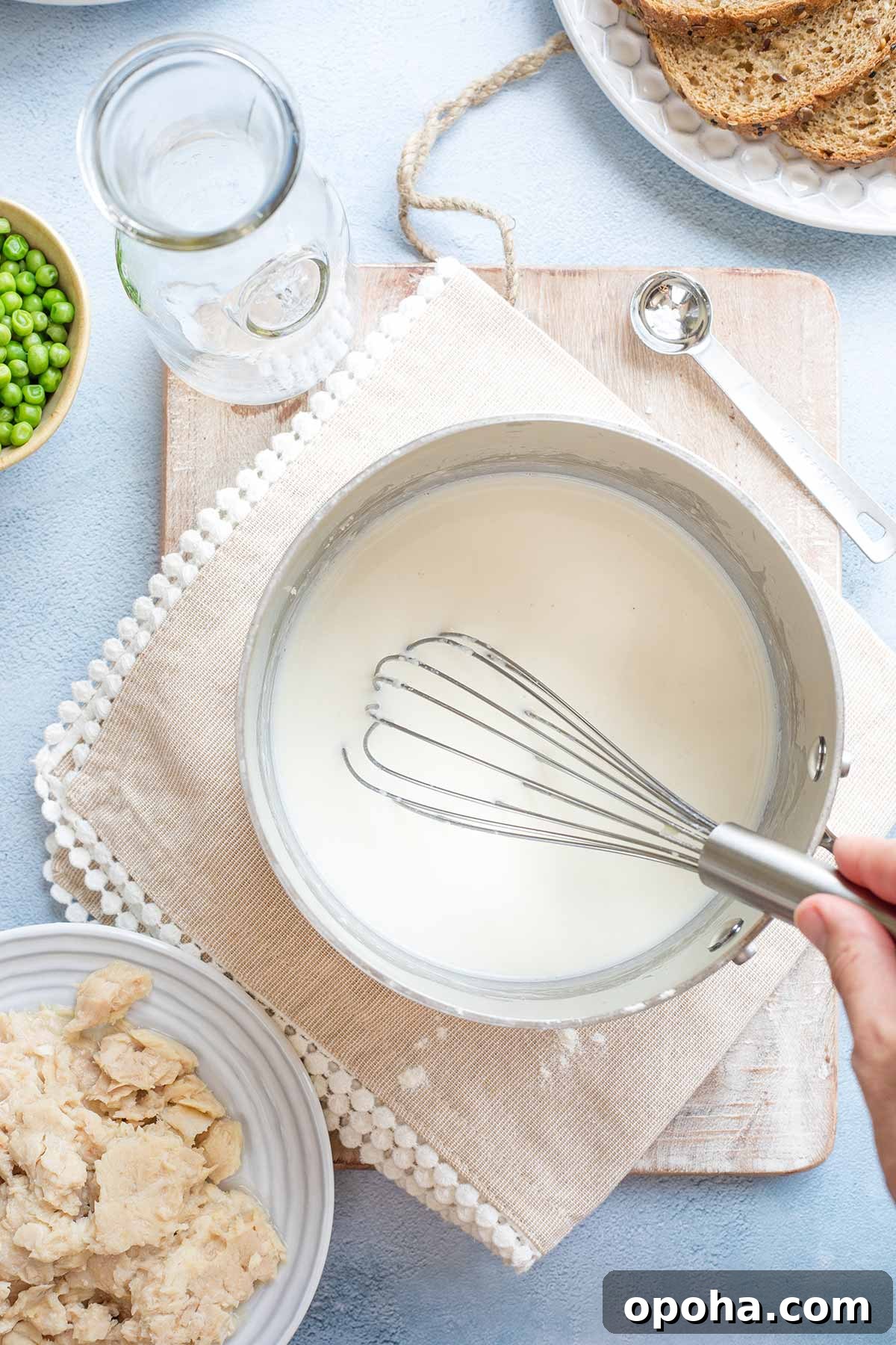 Hand whisking after last addition of milk to tuna cream sauce, while it is still very thin.