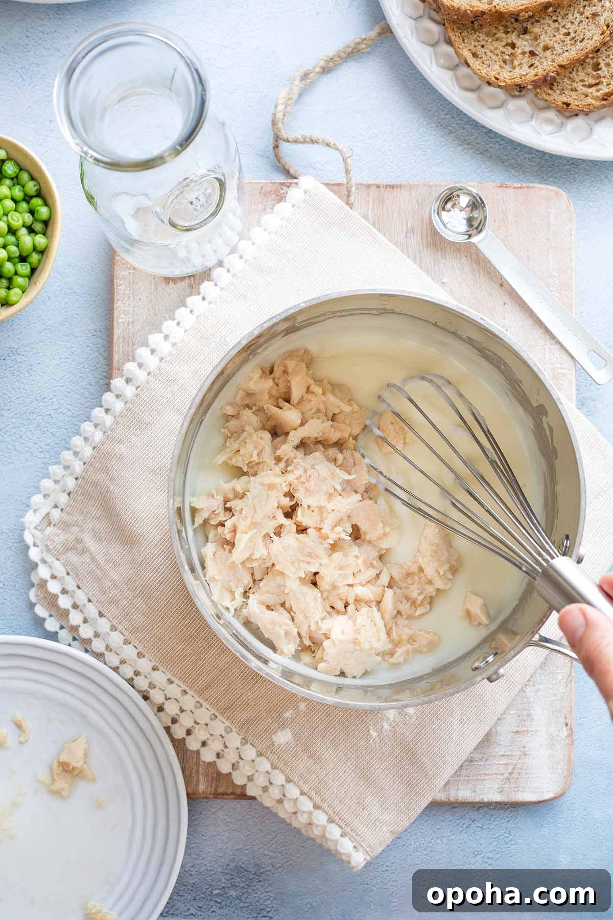 Tuna being added to cream sauce and whisked in.