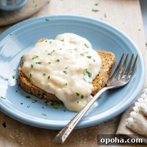 Closeup side view of tuna cream sauce cascading over a piece of toast on light blue plate with fork.