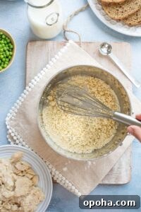 Hand whisking in pan as flour separates into coarse crumbs.