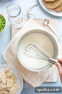 Hand whisking after last addition of milk to tuna cream sauce, while it is still very thin.