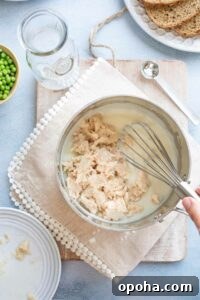Tuna being added to cream sauce and whisked in.
