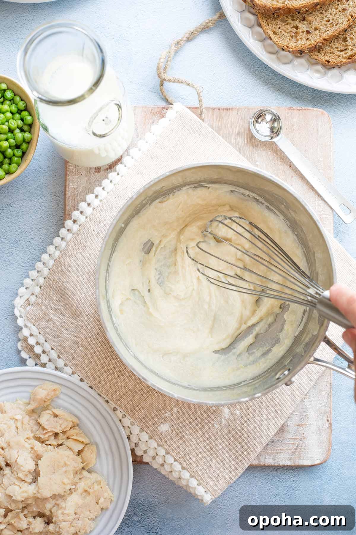 Hand whisking cream sauce in pan.