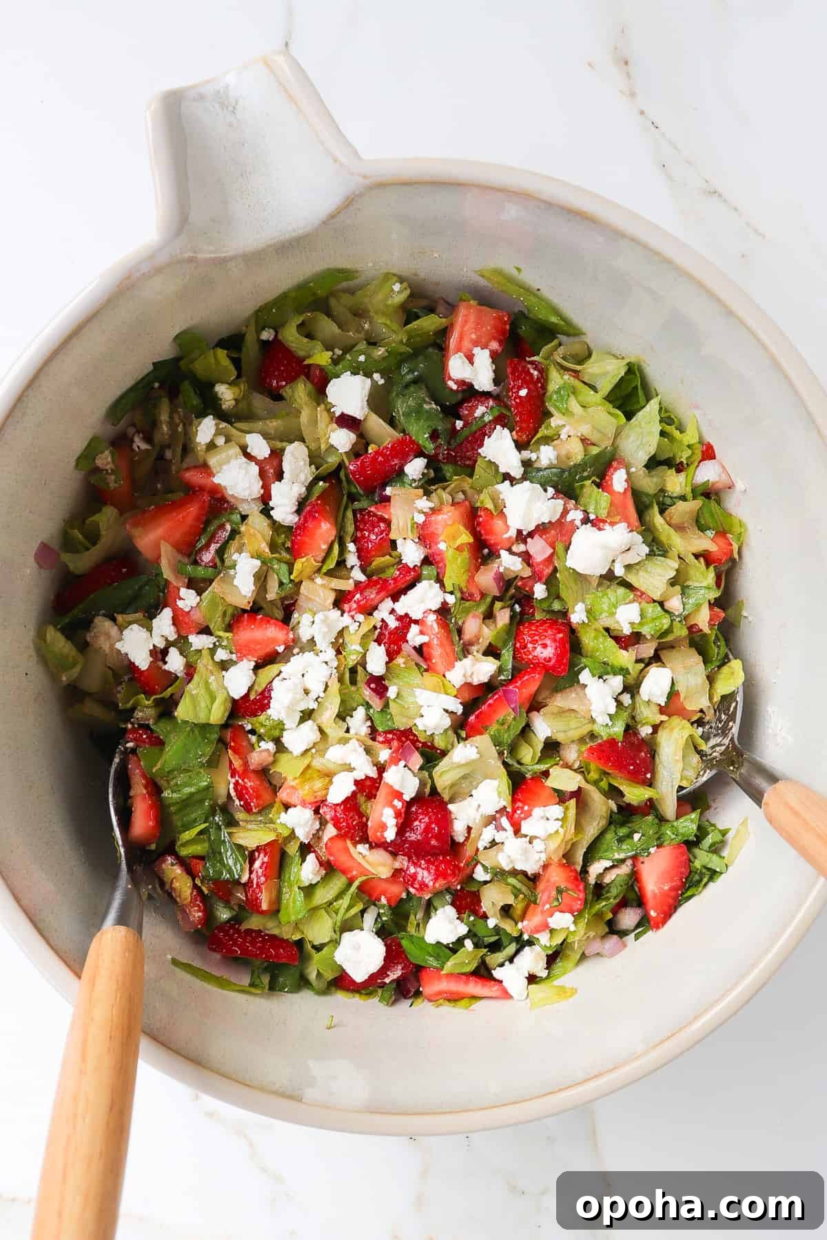 Strawberry and Goat Cheese Salad with Balsamic Glaze 6 Strawberry salad un a mixing bowl with goat cheese crumbled on top.