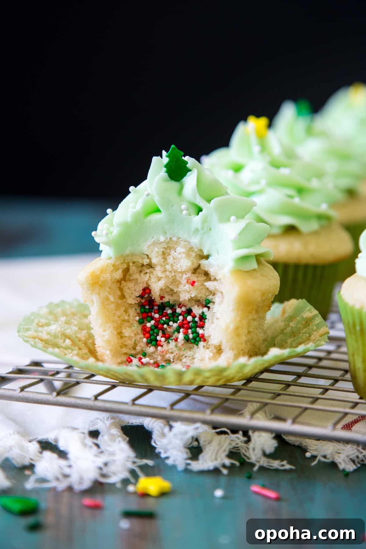 A half eaten piñata cupcakes with Christmas sprinkles spilling out of it.