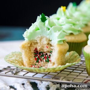 A half eaten piñata cupcakes with Christmas sprinkles spilling out of it.