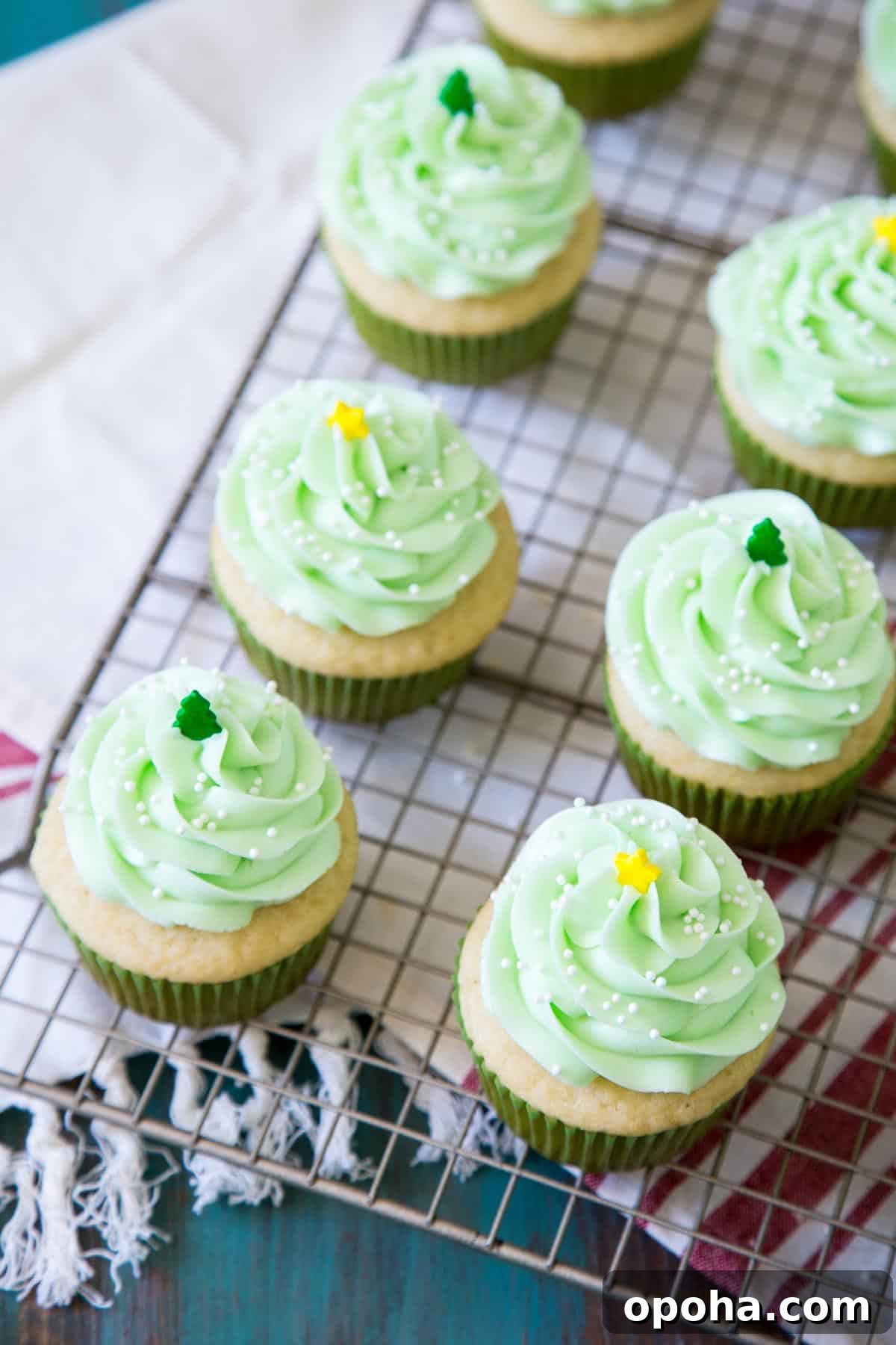 Piñata cupcakes with pastel green mint buttercream sitting on a wire rack.