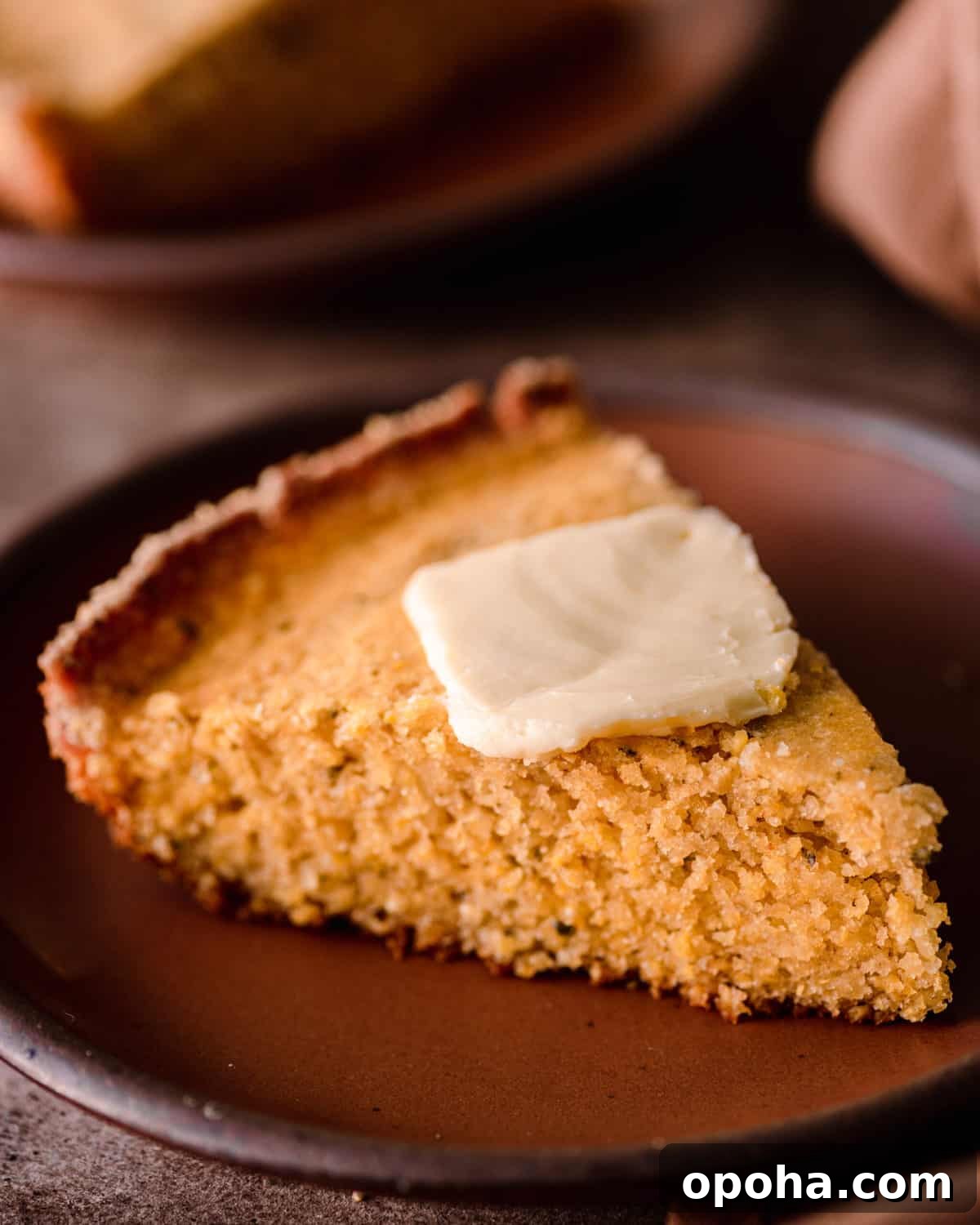 slice of vegan cornbread with a pat of butter on a plate