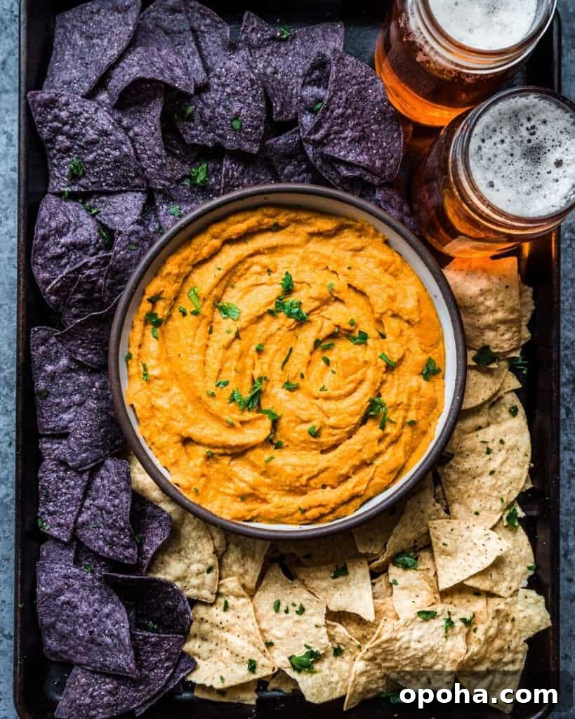 Cheesy Buffalo Cauliflower Dip in a bowl surrounded by tortilla chips and beers