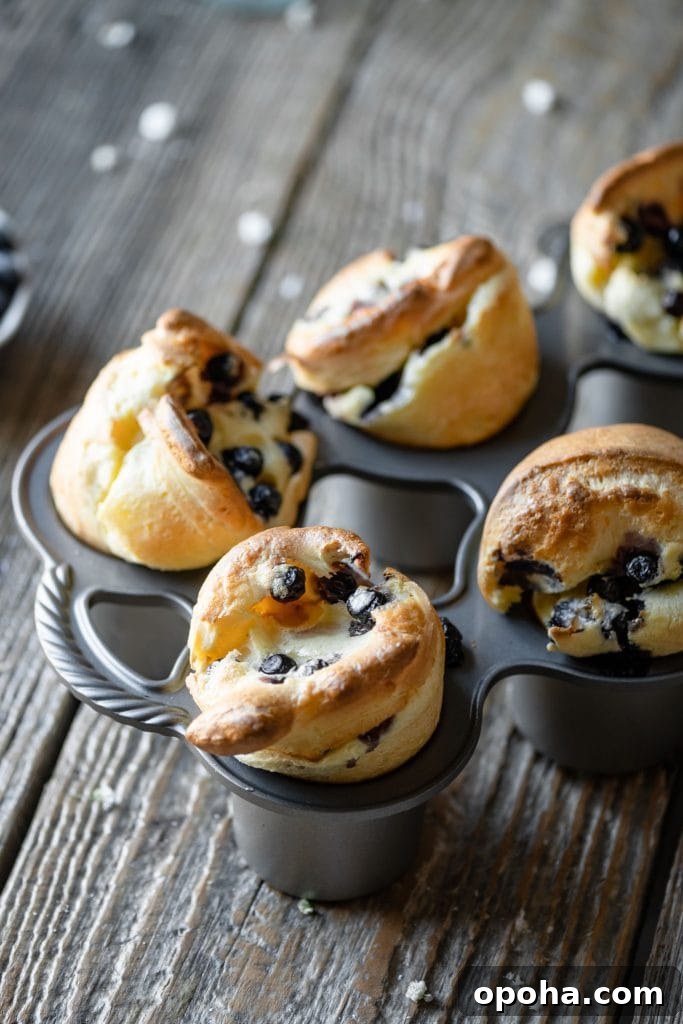 Fluffy Blueberry Popovers: Light, Crispy Breakfast Treat 4 Blueberry popovers in popover tin on table.