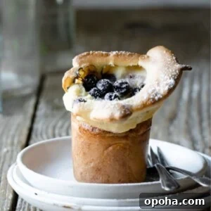 Fluffy Blueberry Popovers: Light, Crispy Breakfast Treat 7 Blueberry popover on a stack of plates with two forks.
