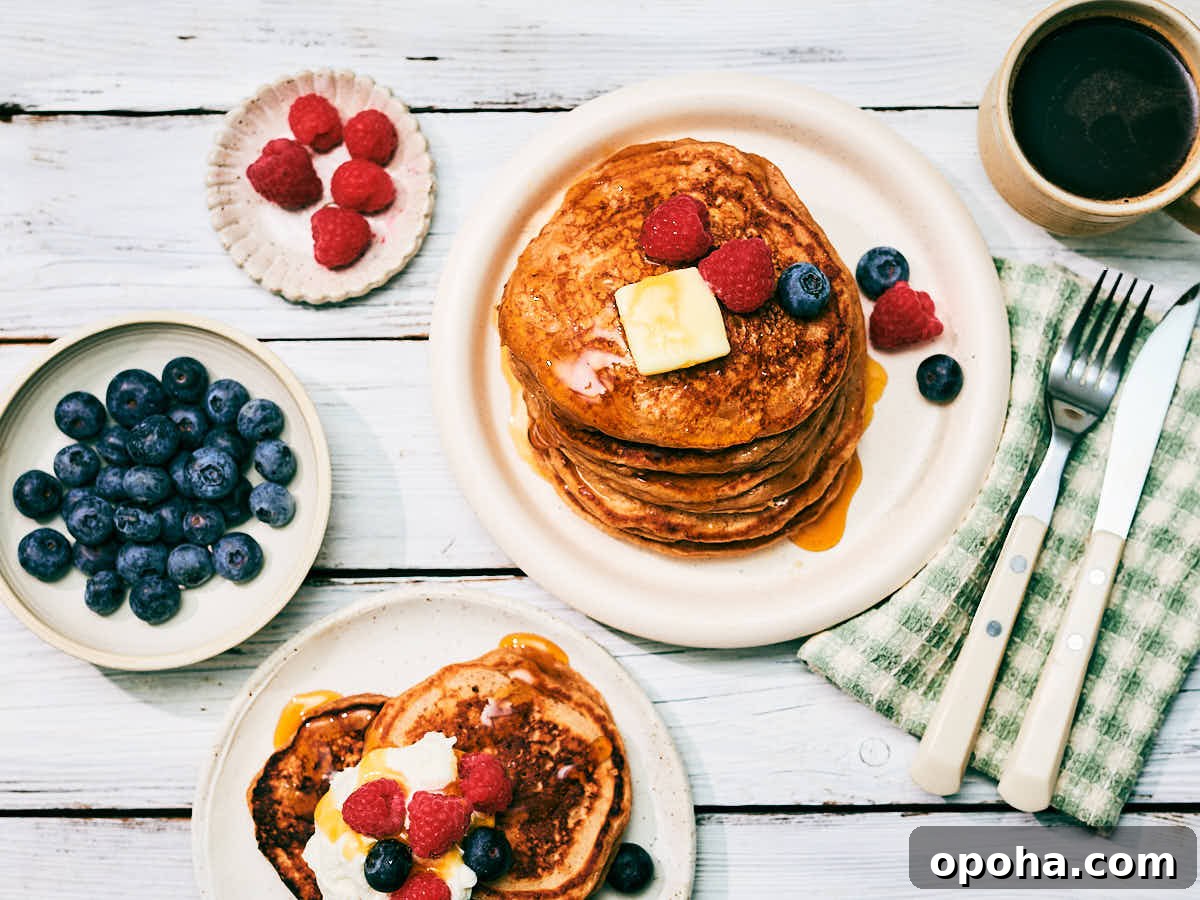 High-Protein Cottage Cheese Pancakes for Muscle Gain and Weight Loss 3 High protein Cottage Cheese Pancakes on plates topped with berries, butter, maple syrup on a breakfast table.