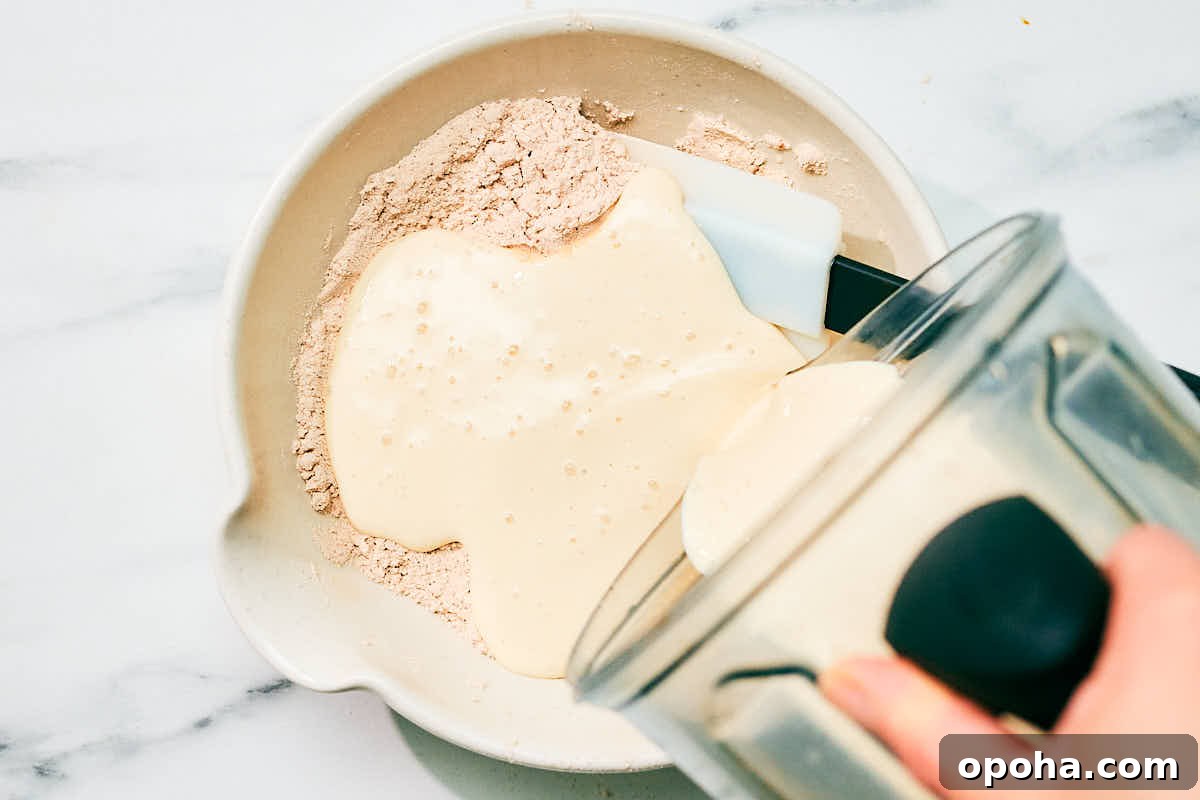 High-Protein Cottage Cheese Pancakes for Muscle Gain and Weight Loss 8 Adding wet ingredients from blender to dry ingredients in a bowl.