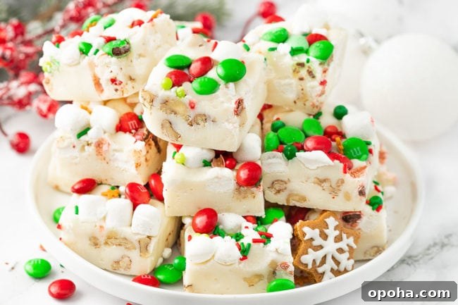 a stack of White Christmas Fudge with holiday candies on a white platter