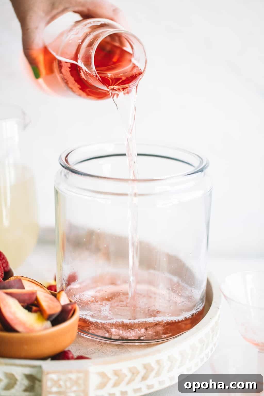 Rosè wine being poured into a glass pitcher. 