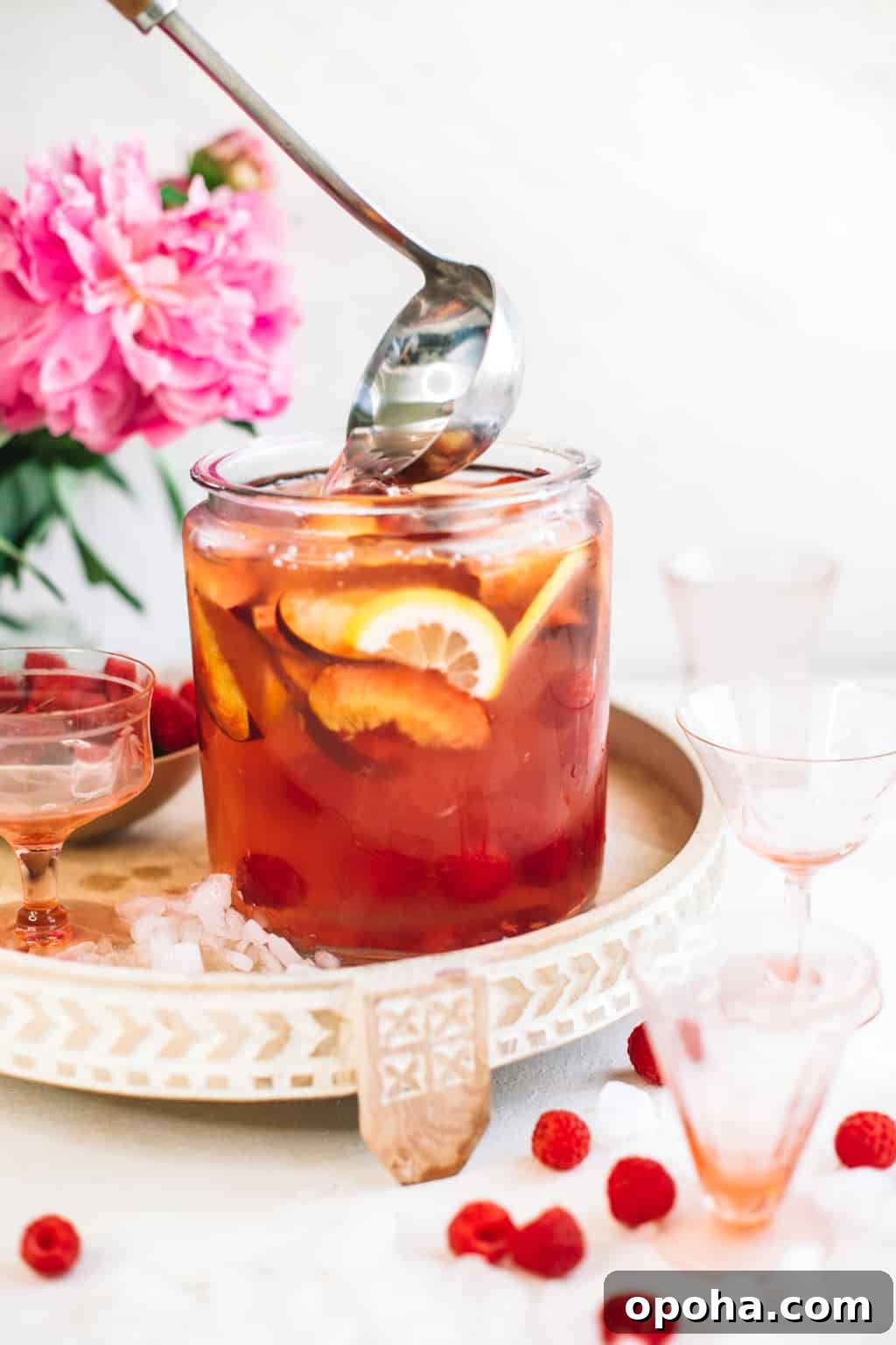 Ladle scooping out batch of sangria in a glass pitcher. 
