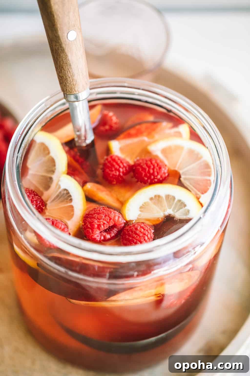 Fresh pitcher of rosè sangria with fresh raspberries and lemon slices.