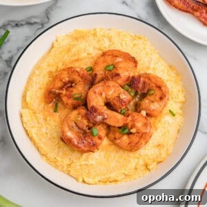 Creamy Shrimp and Grits with Cheddar and Garlic 12 A bowl of cheesy shrimp and grits garnished with green onions and bacon.