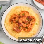 Creamy Shrimp and Grits with Cheddar and Garlic 13 A bowl of cheesy shrimp and grits garnished with green onions and bacon.