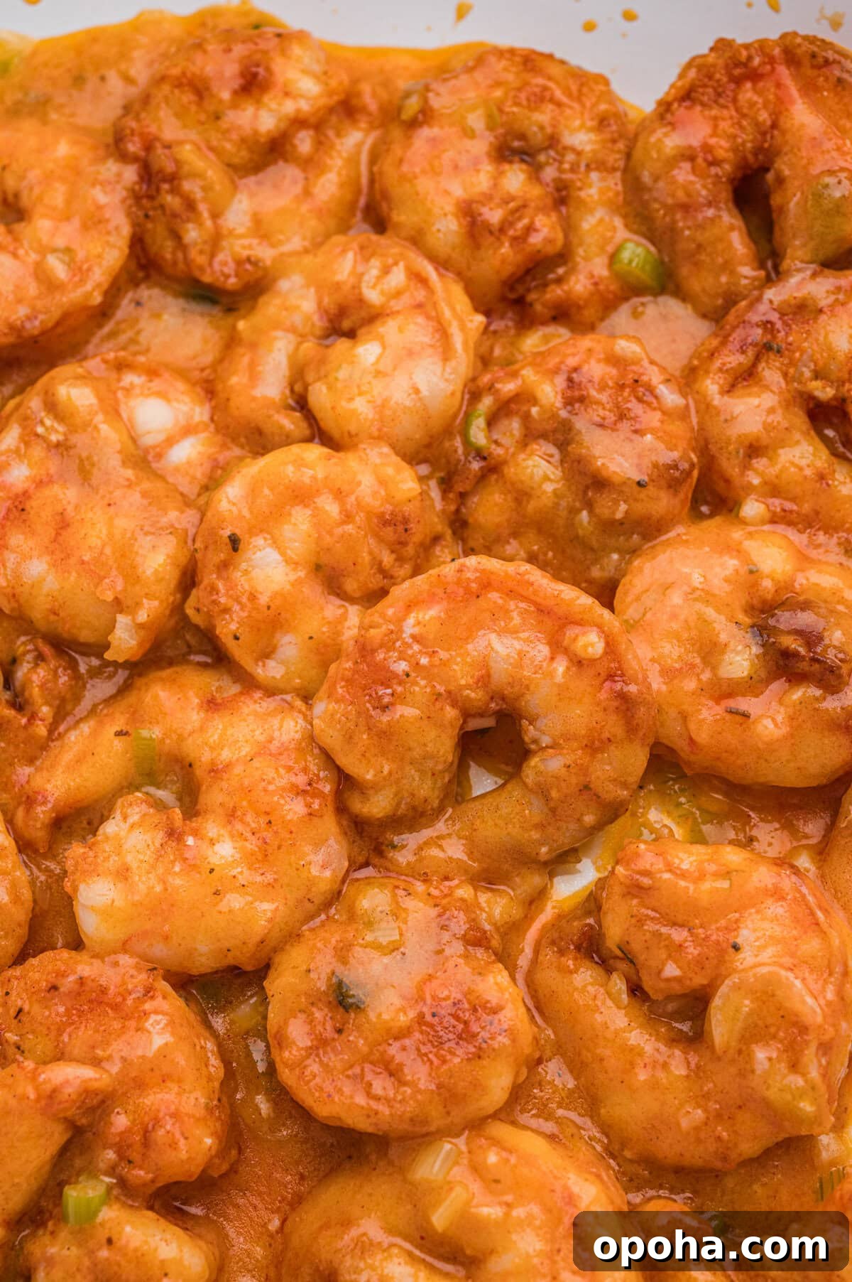 Creamy Shrimp and Grits with Cheddar and Garlic 9 Close-up of cooked seasoned shrimp coated in a creamy orange sauce.