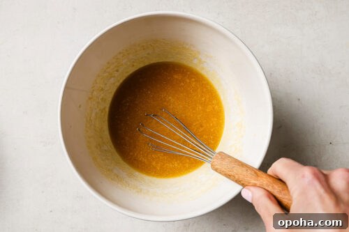 Rich pecan pie brownie batter in a white mixing bowl, ready to be poured into the pan for baking.