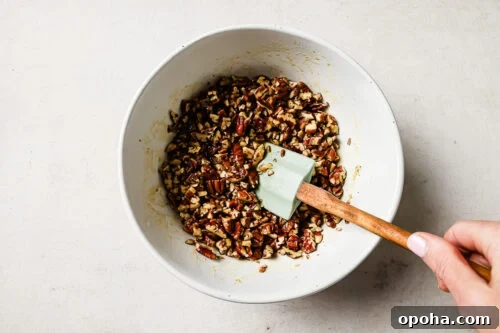 Pecan pie topping mixture in a white bowl with a spatula.