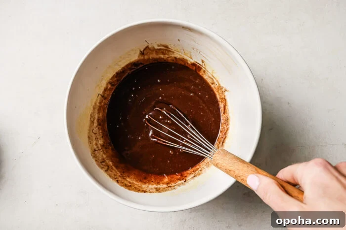 Rich pecan pie brownie batter in a white mixing bowl, ready to be poured into the pan for baking.