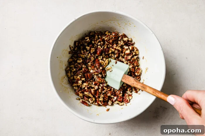 Pecan pie topping mixture in a white bowl with a spatula.
