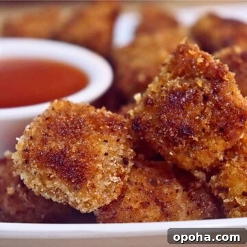 chicken nuggets on a plate, with a small bowl of tomato ketchup on the side.
