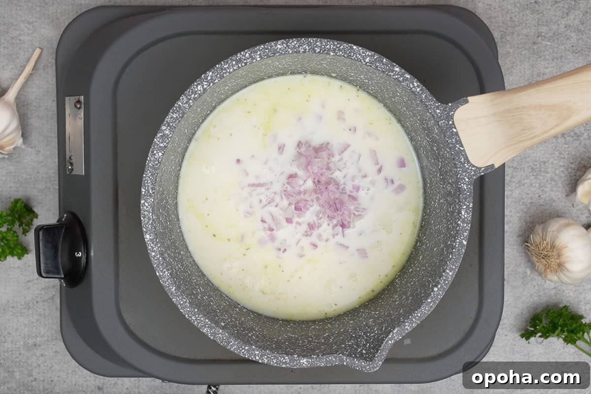 Chicken broth, milk, garlic and onion mixed in a pan.