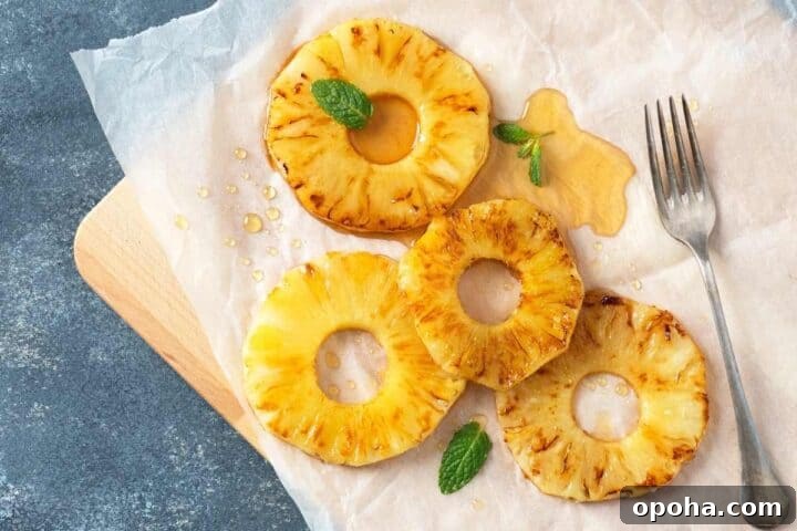 Air Fryer Cinnamon Pineapple Recipe — Grilled Flavor in Minutes 8 grilled pineapple slices placed on a parchment paper and drizzled with honey on top