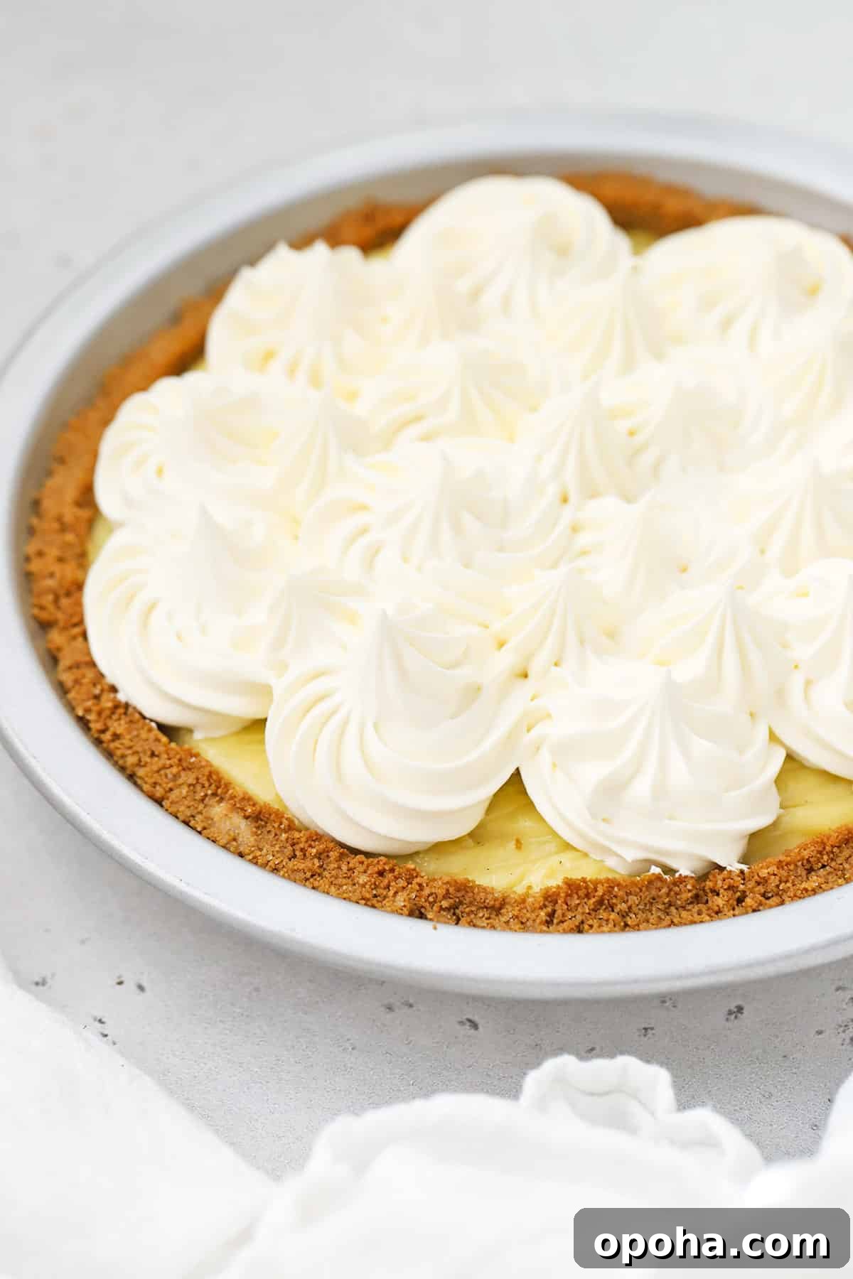 Gluten-Free Banana Cream Pie Recipe — Light, Silky & Delicious 7 Front view of a gluten-free banana cream pie topped with swirls of whipped cream