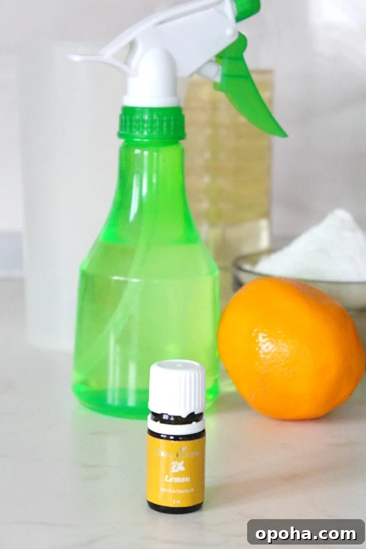 DIY Lemon Disinfectant Spray for a Fresh, Germ-Free Home 2 Image of homemade natural disinfectant for home in a green spray bottle, next to a bottle of essential oils and lemon fruit
