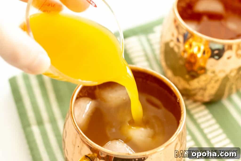 Mango Mule Mocktail Recipe: Refreshing Non-Alcoholic Cocktail 5 hand adding mango nectar