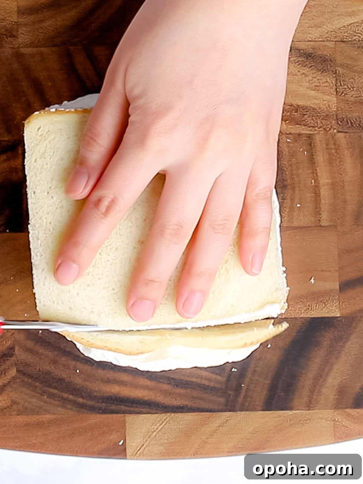Japanese Fruit Sandwich (Strawberry Sando): How to Make フルーツサンド 12 Cutting the crust off of white sliced bread laid on a wooden cutting board.