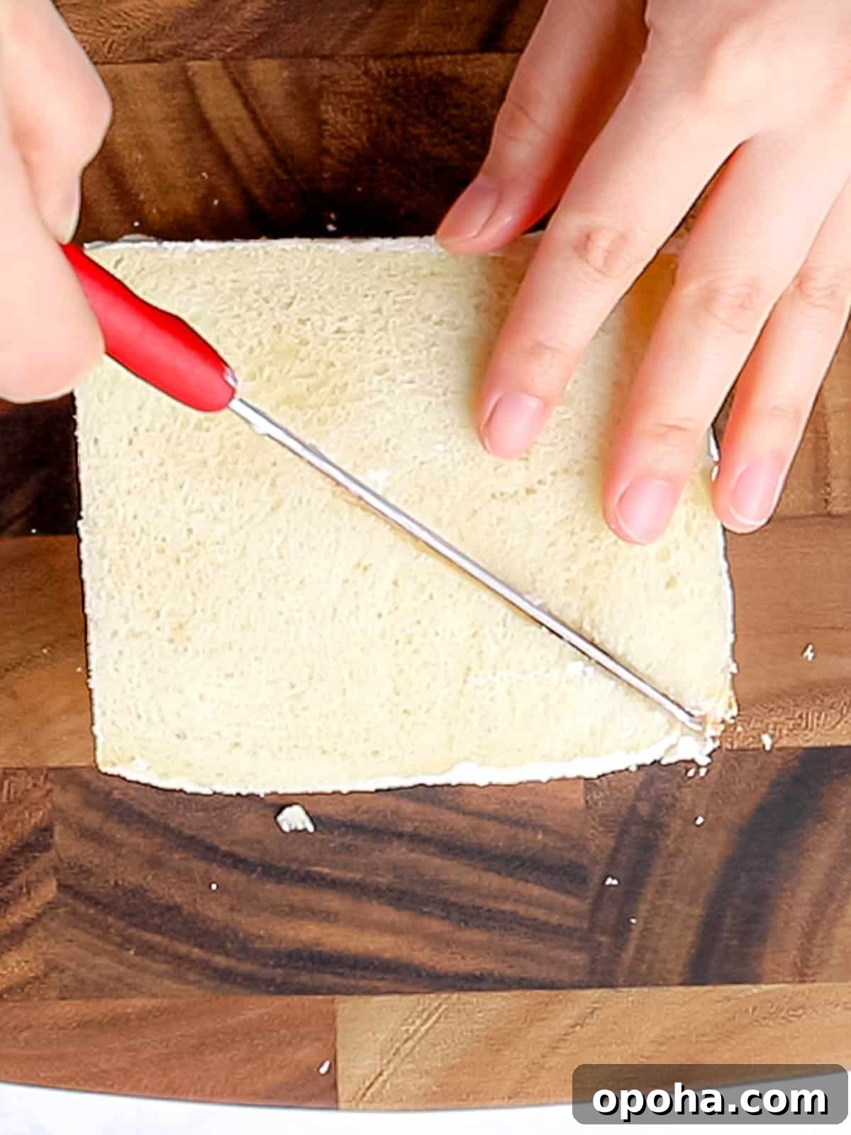 Japanese Fruit Sandwich (Strawberry Sando): How to Make フルーツサンド 13 Cutting fruit sando in half with a knife on top of a wooden cutting board.