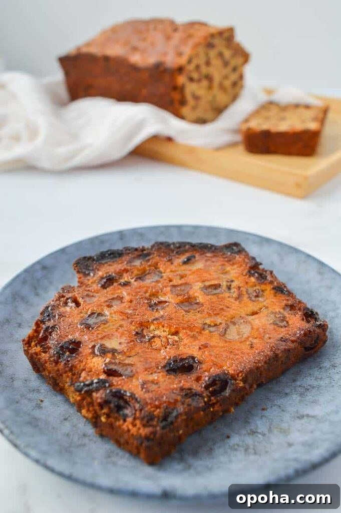 Traditional Irish Barmbrack Recipe for Perfect Fruit Tea Bread 4 A toasted slice of tea brack with a loaf in the background