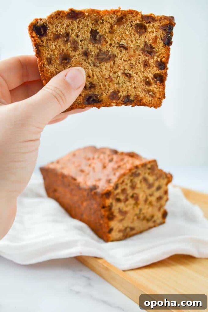 Traditional Irish Barmbrack Recipe for Perfect Fruit Tea Bread 8 A hand holding a slice of barmbrack with a cut loaf in the background