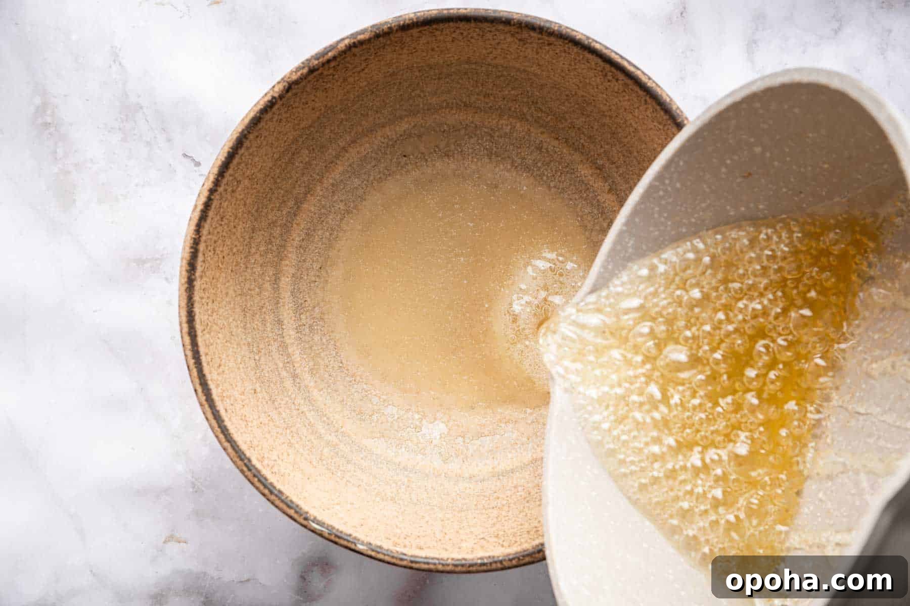 How to Make Homemade Marshmallows from Scratch: Fluffy Recipe 7 Pouring boiling sugar into bloomed gelatin in a brown bowl.