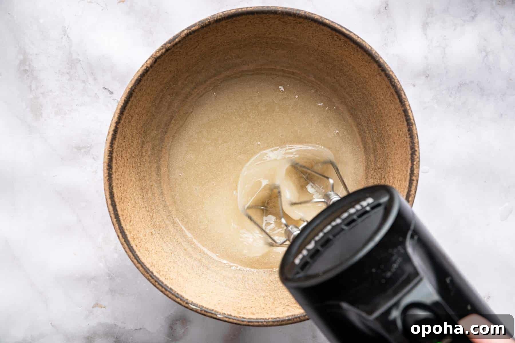 How to Make Homemade Marshmallows from Scratch: Fluffy Recipe 8 Black hand mixer blending tan cream in bowl.