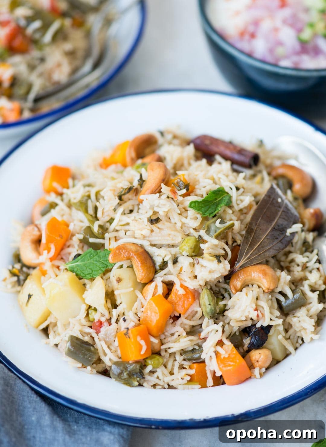 Close up shot of Vegetable pulao served in a white plate. Pulao is made with vegetables, whole spices and cashews.