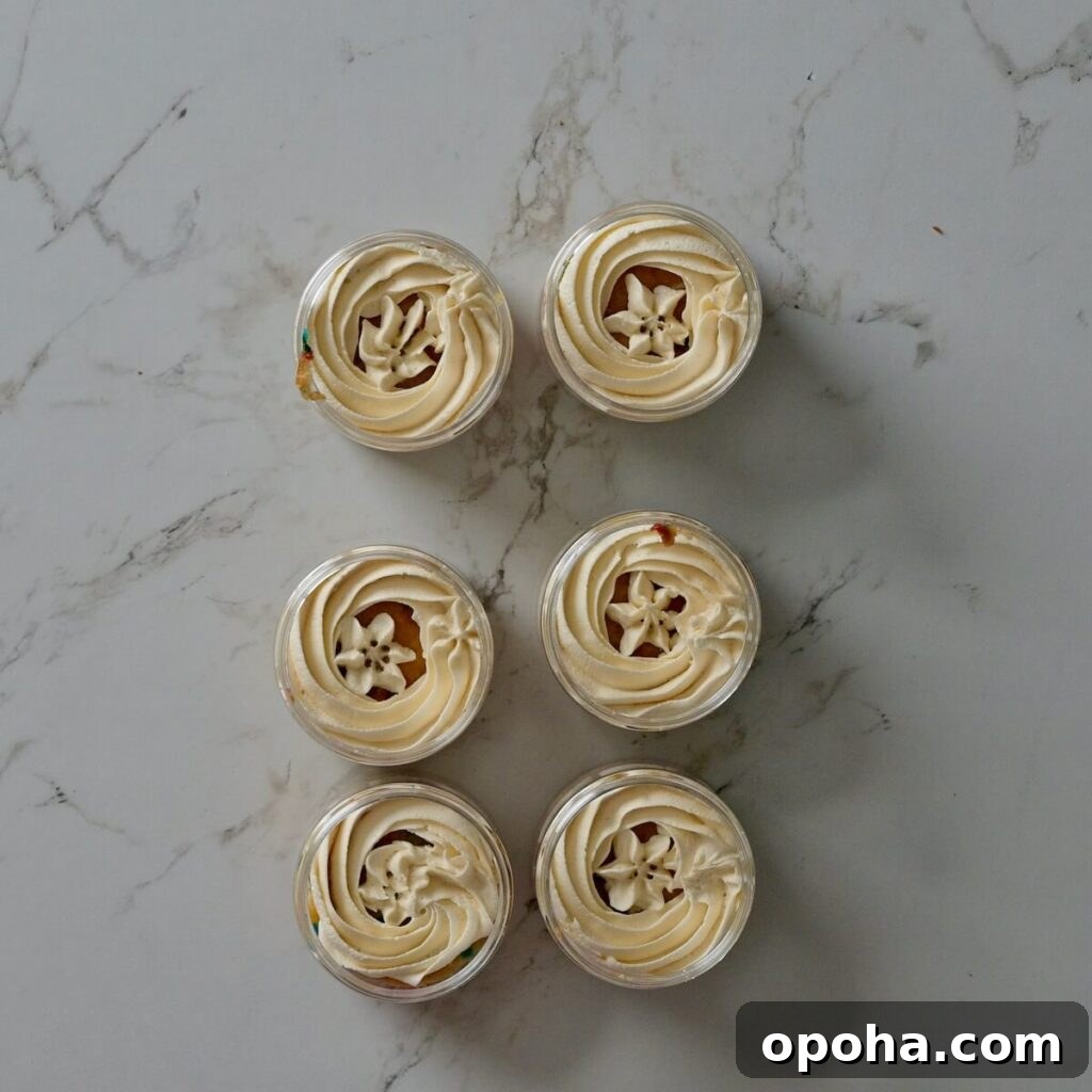 Mason Jar Cake Recipe: Layered Dessert in a Jar 12 cakes in a jar with the first layer of frosting on top of the cake.