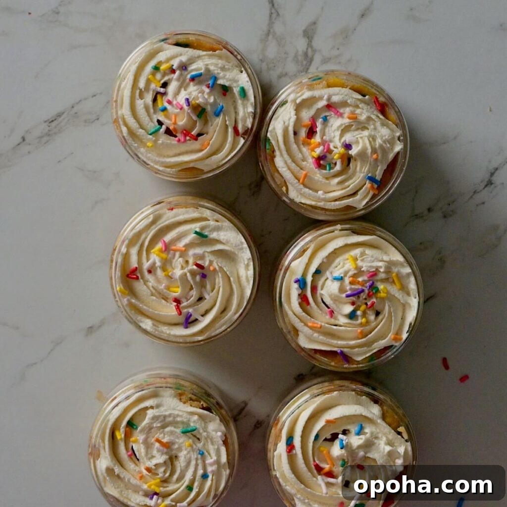 Mason Jar Cake Recipe: Layered Dessert in a Jar 13 cakes in a jar with frosting and sprinkles on top before closing and adding the small spoon.