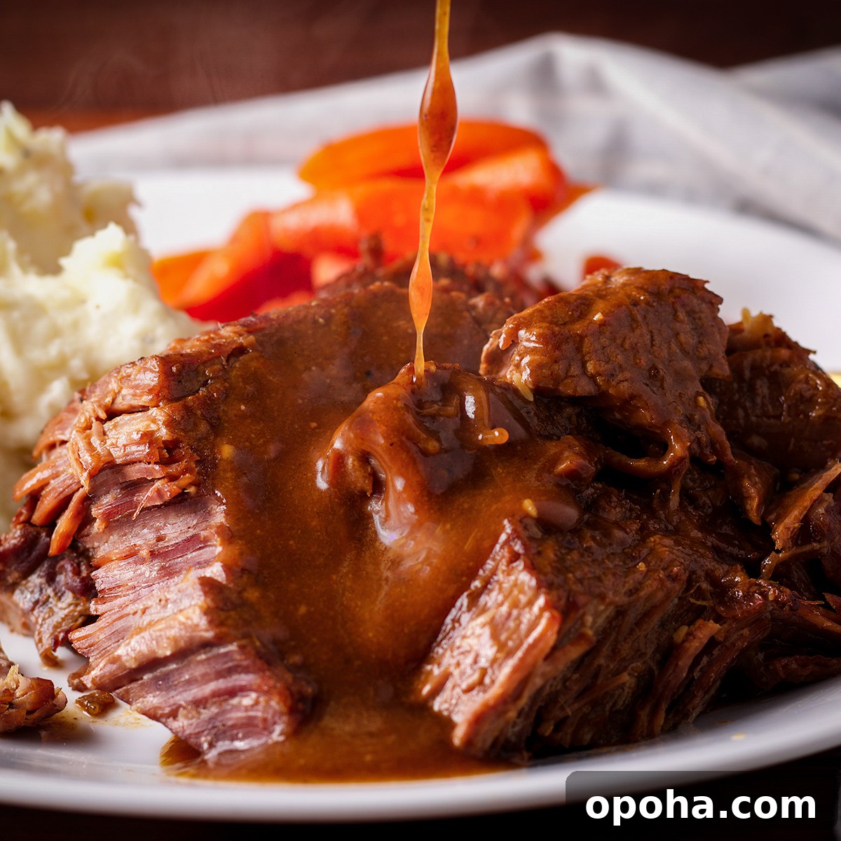 Someone pouring fennel and coriander gravy over a plate full of tender, cooked Tri Tip roast.
