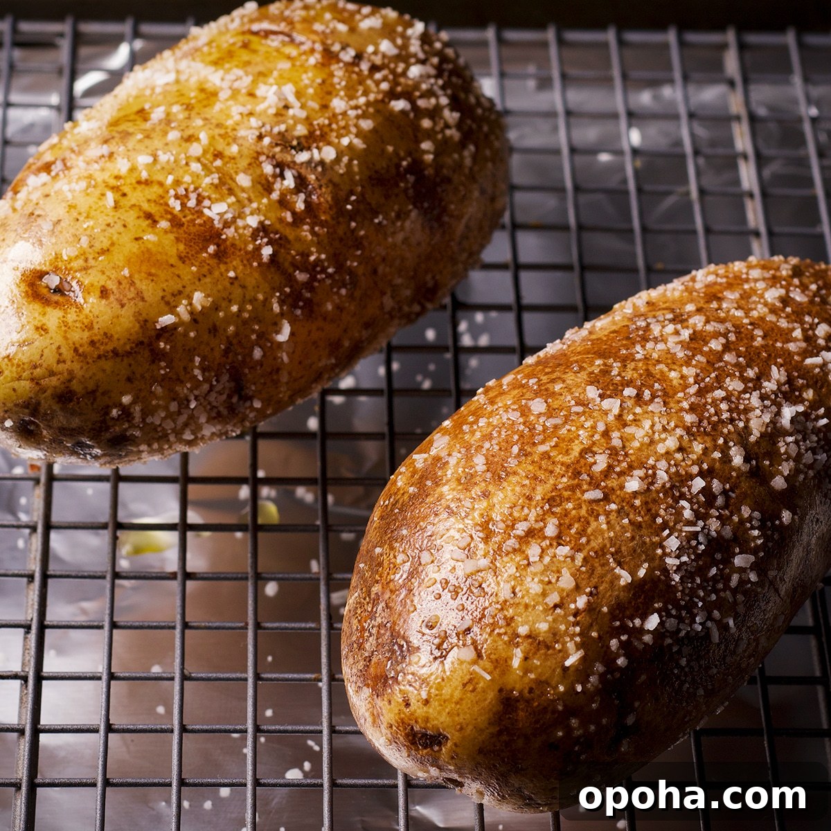 Perfect Crispy Baked Potatoes: Oven-Roasted Recipe and Tips 6 Two raw baking potatoes on rack set inside a baking sheet ready to bake.