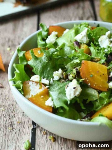 Eye-level view of golden beet salad in a white bowl on a wood surface.