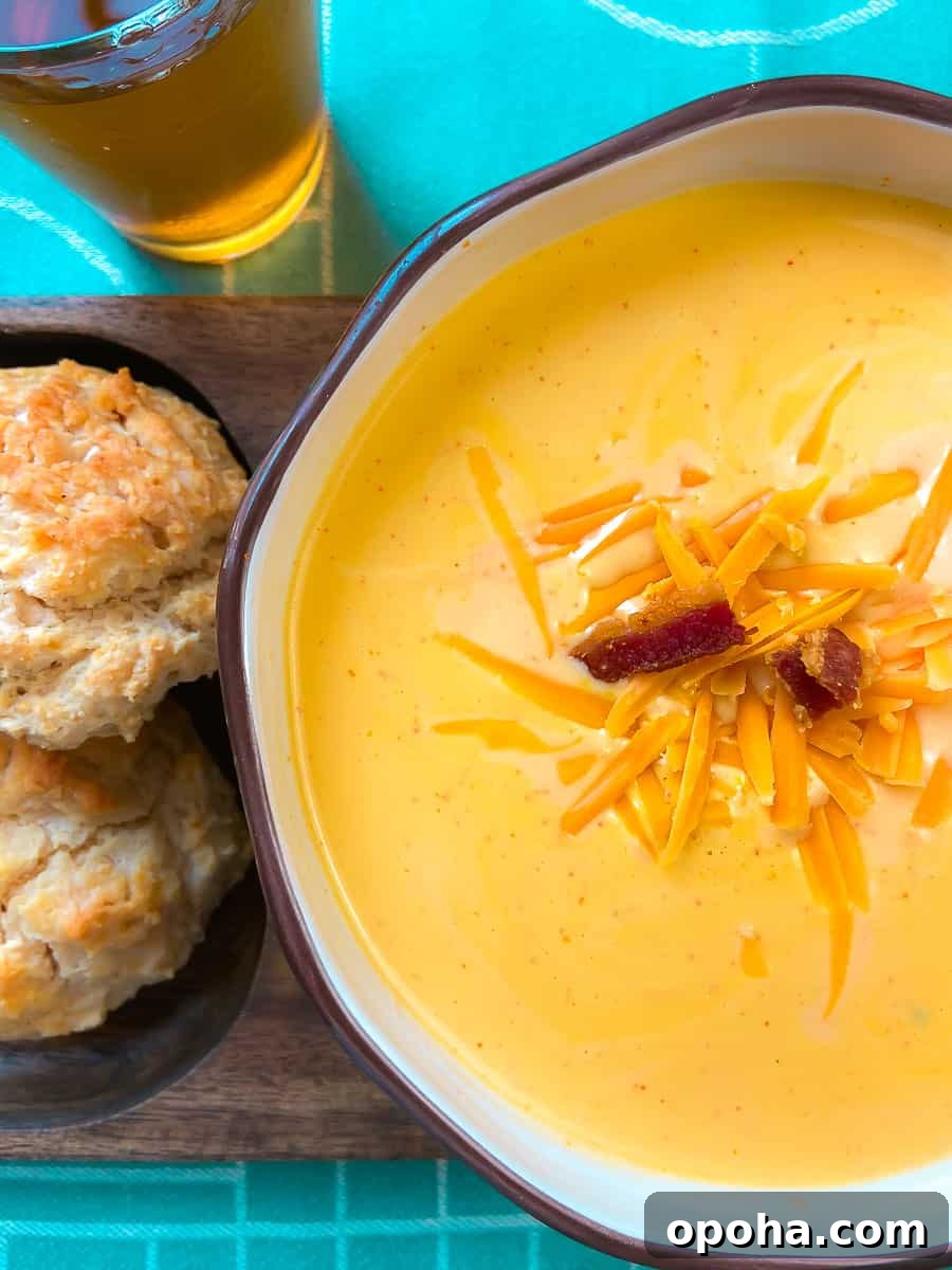 Soup in a bowl with a side of amber beer and biscuits.
