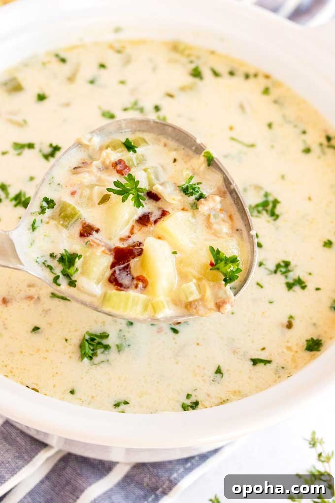 A ladle full with creamy clam chowder and topped with crispy bacon