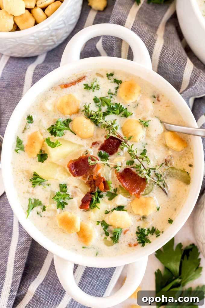 Clam chowder with bacon on top in a white bowl.