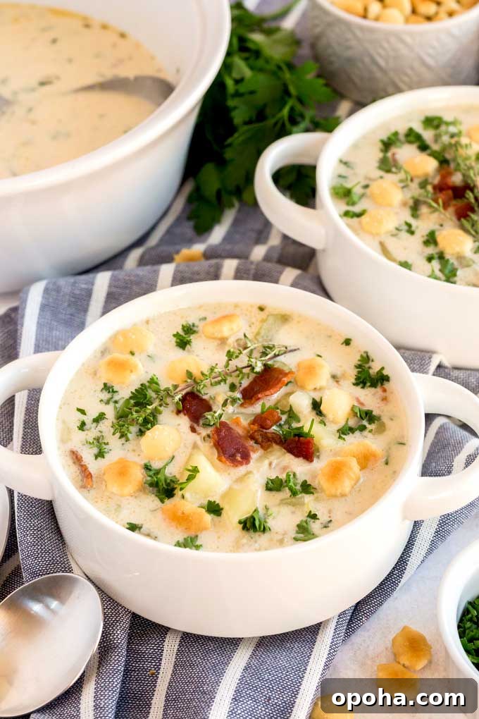 Creamy clam chowder topped with bacon an oyster crackers serve in white bowls